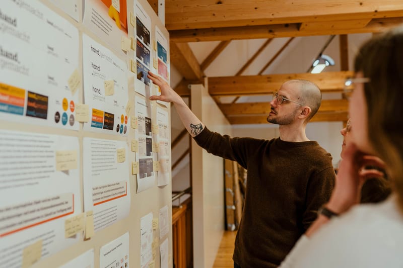 Diskussion vor einer Wand mit Designentwürfen für hand.gemacht